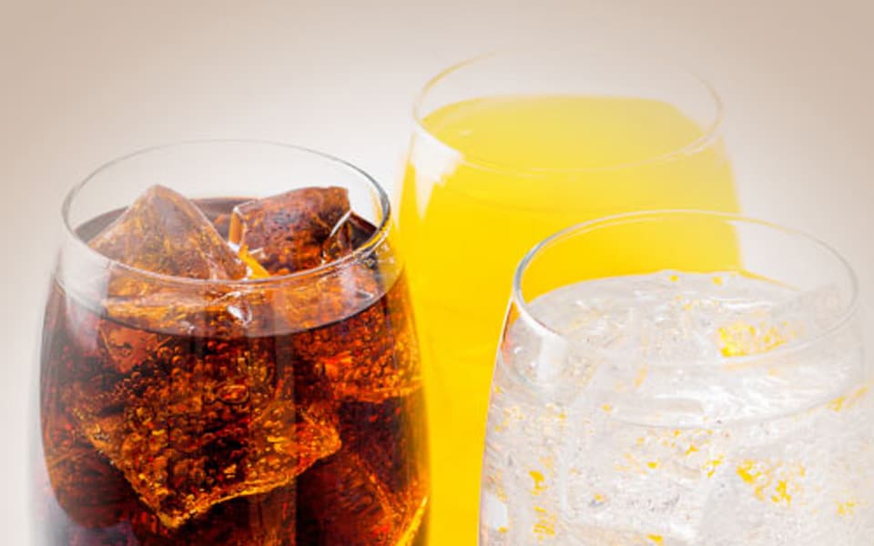 Three glasses filled with different carbonated beverages and ice, showcasing variety in soft drink packaging