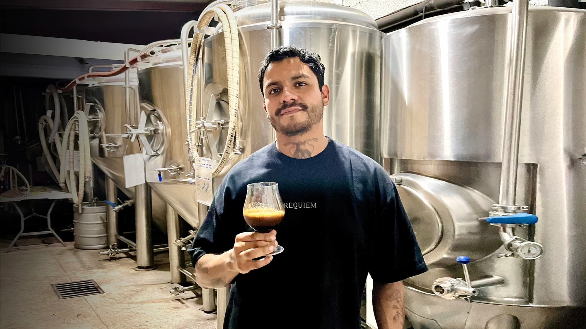 Santa Sabina brewer holding a fresh glass of craft beer inside the brewery
